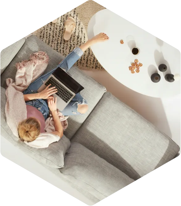 Vrouw werkt op laptop in een comfortabele woonkamer, gezien van bovenaf.