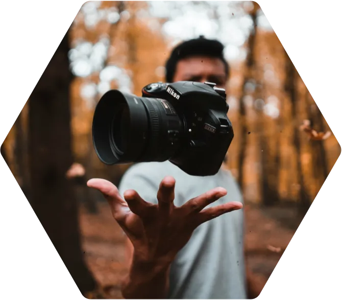 Man werpt foto toestel omhoog in één hand in het bos.